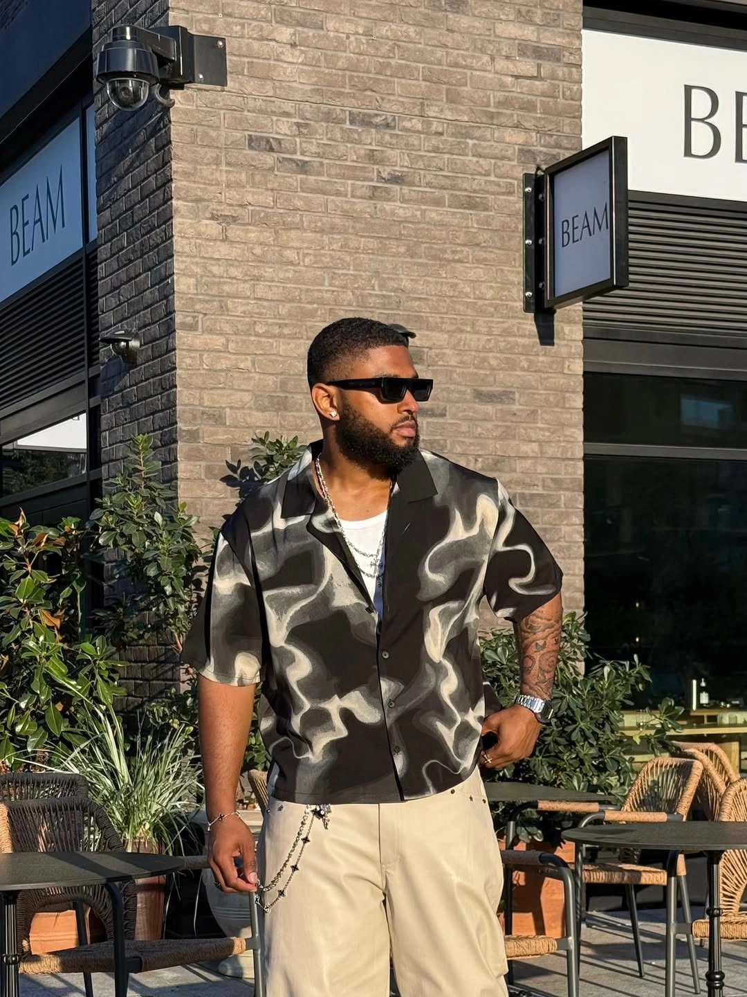 Abstract black short-sleeve shirt with cream pleated trousers