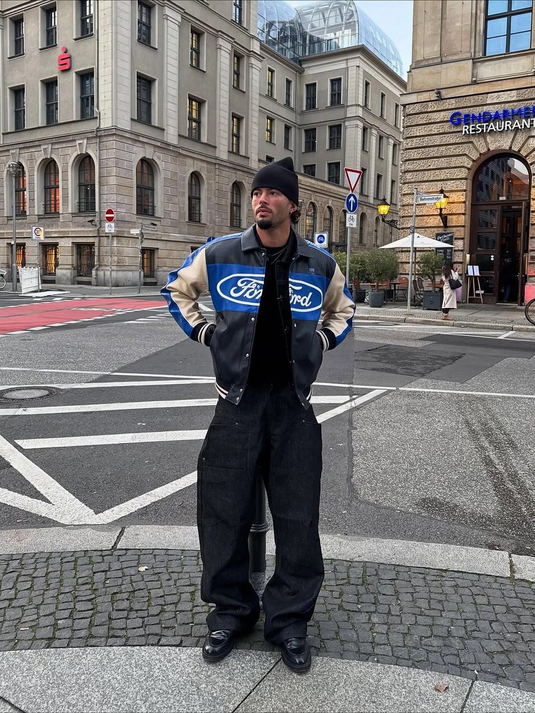 Blue varsity jacket with black trousers, beanie, and dark boots