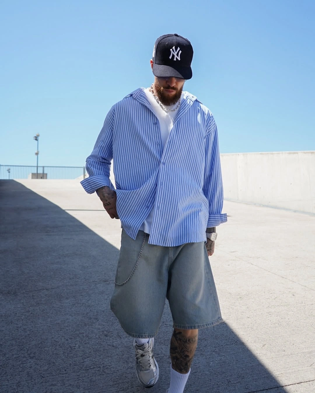 Blue striped oversized shirt with gray long shorts and white sneakers