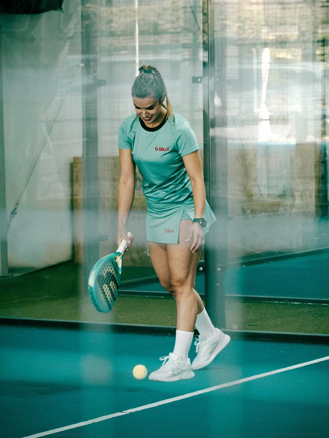Mint athletic top with pale shorts and white shoes on padel court