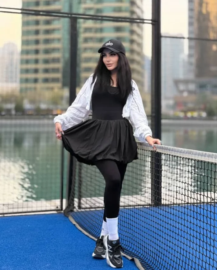 Black pinafore dress over white blouse with leggings for padel