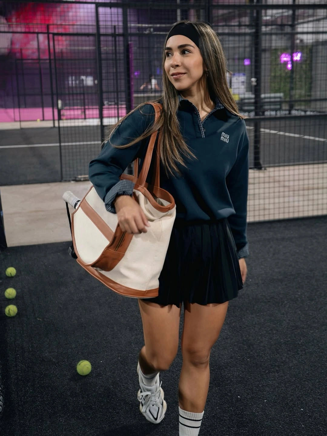 Navy sweatshirt with black pleated skirt and large tote at padel court