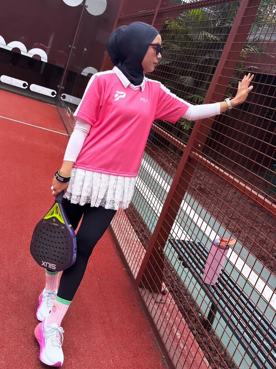 Pink polo with white sleeves, fringed skirt, and black leggings
