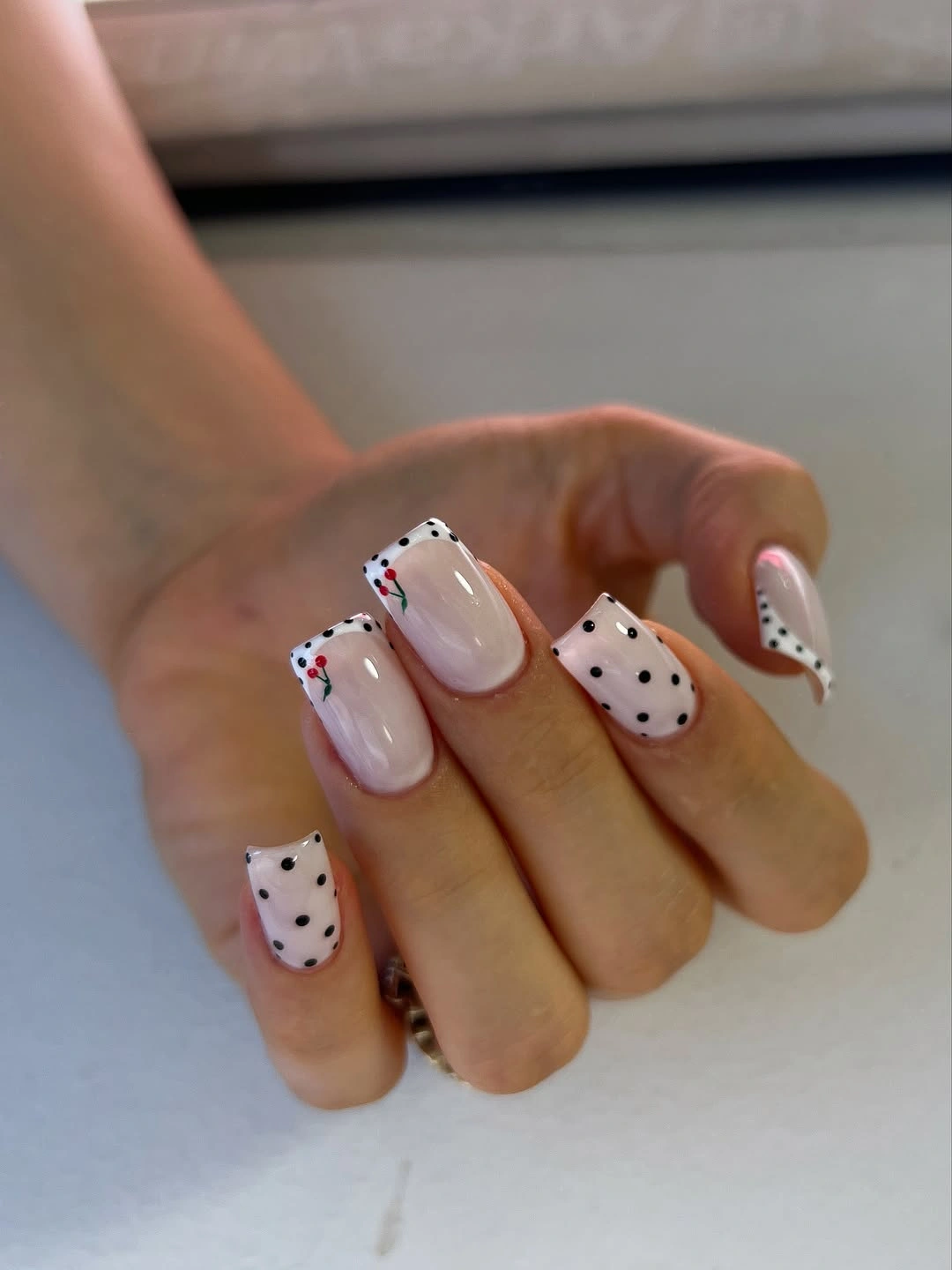 soft pink square nails with black dots and tiny red details