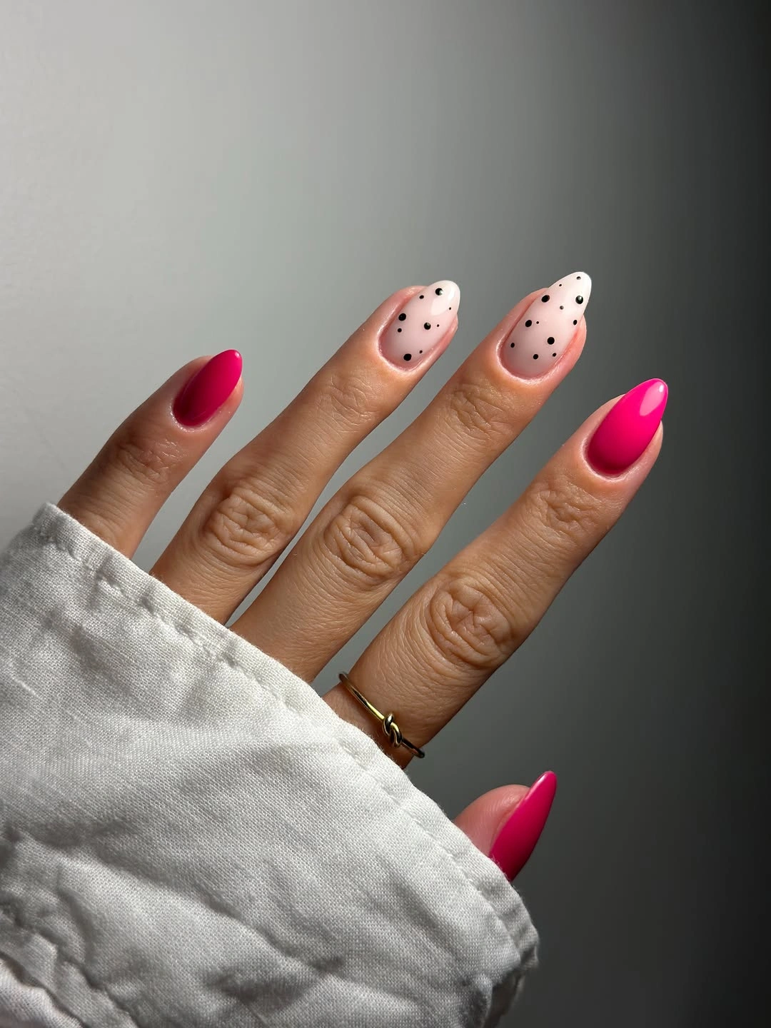 nude nails with white dotted French tips beside hot pink accent nails