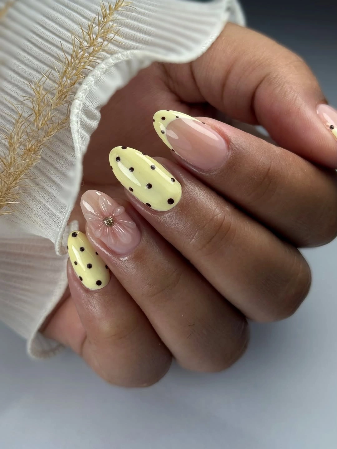 pale yellow and nude almond nails with black polka dots and flower detail
