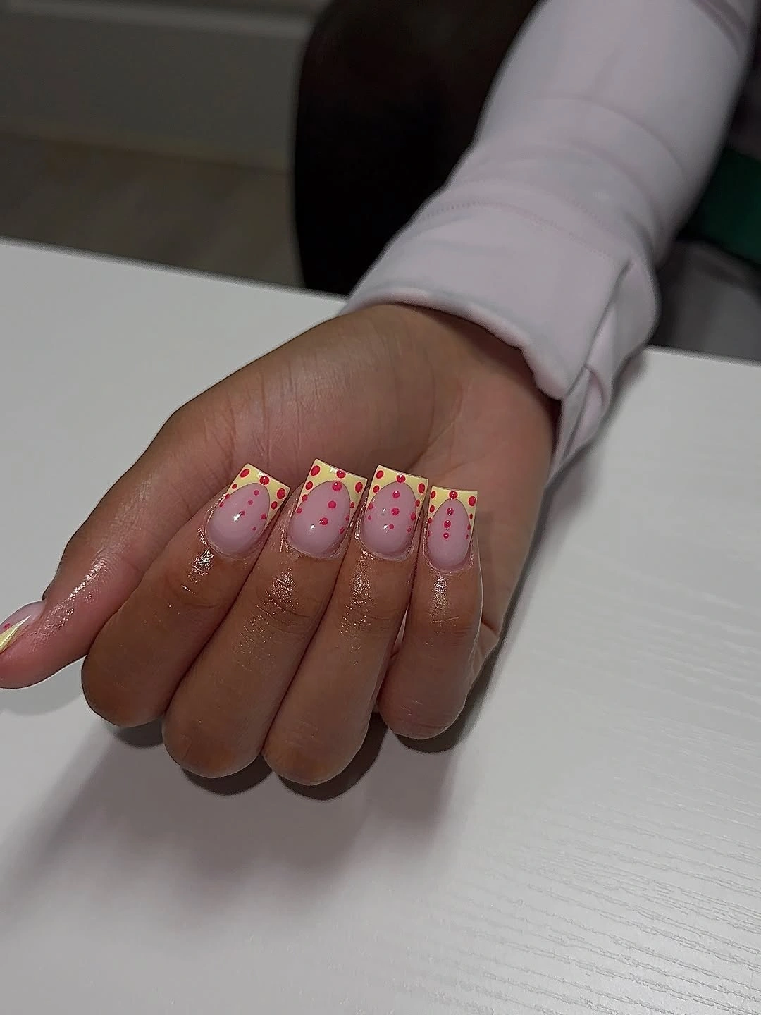 square nails with butter yellow French tips and soft pink polka dots