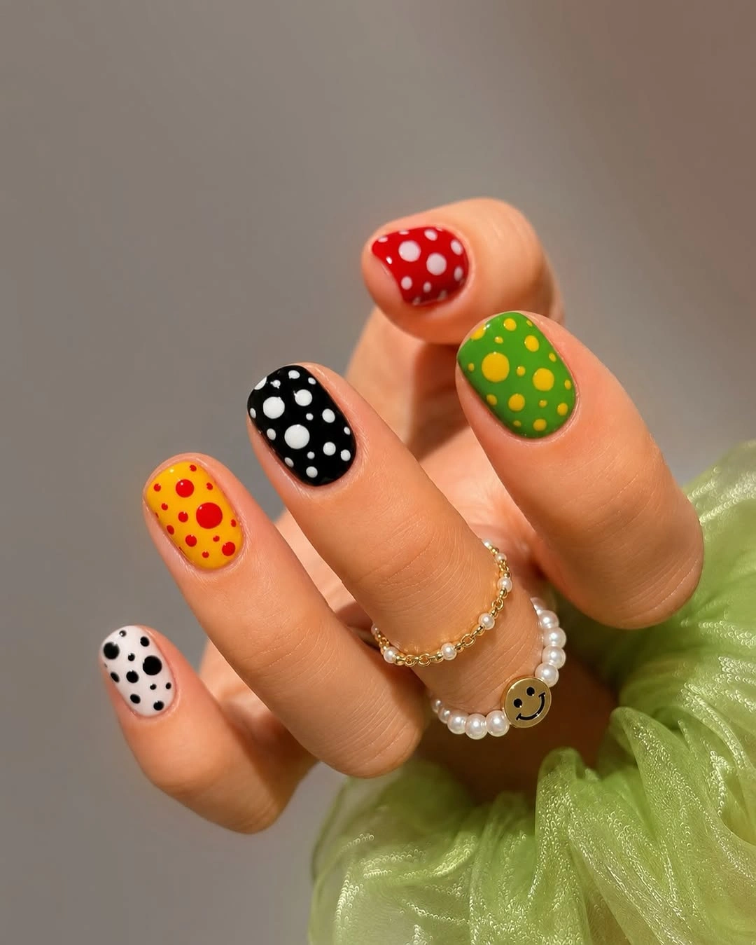 short nails with red green yellow black and white polka dot designs