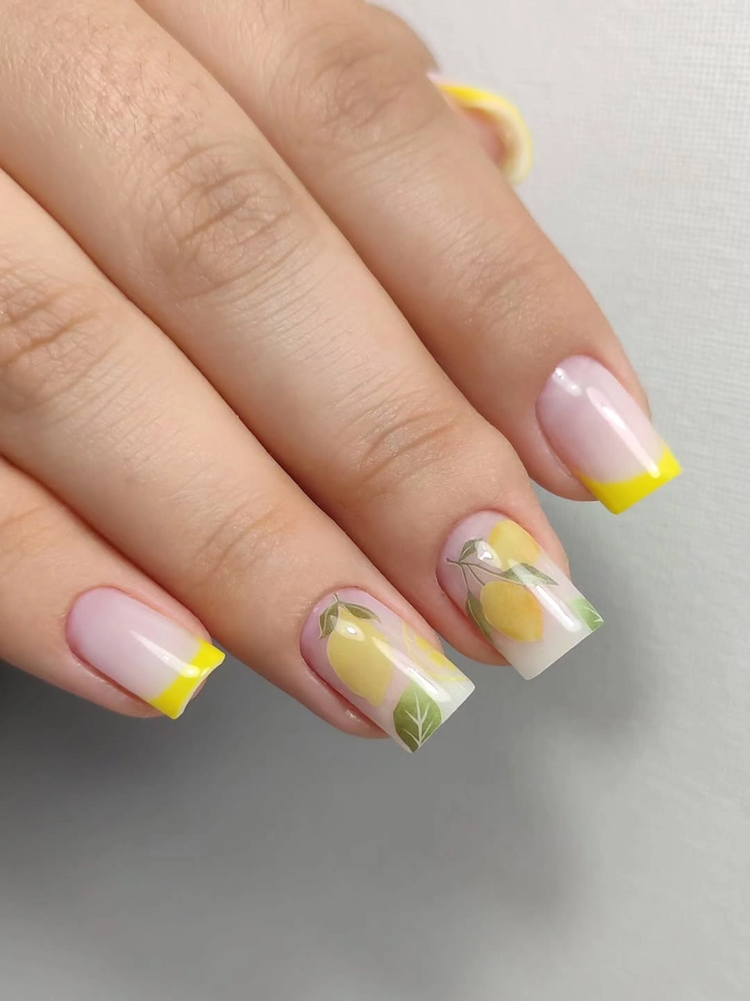 Short square nails with yellow tips and lemon leaf accents