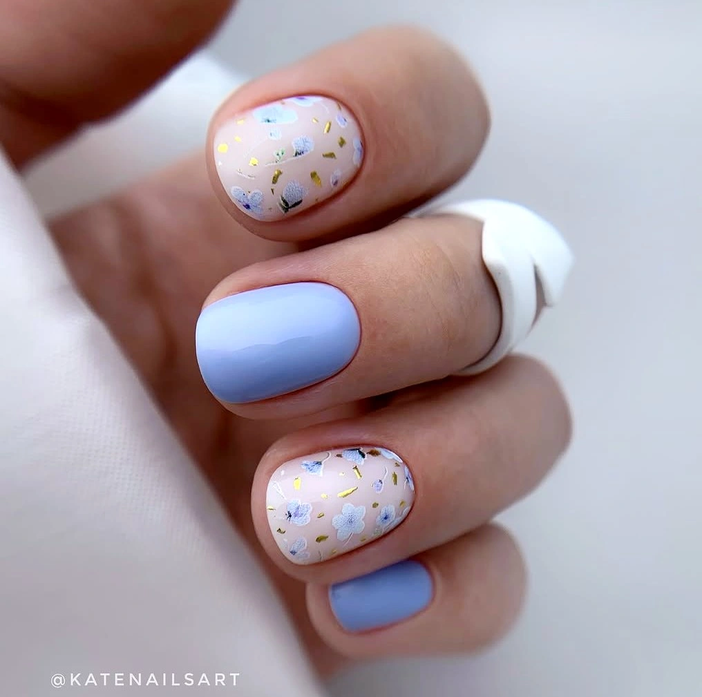 Short rounded nails with periwinkle polish and tiny floral accents