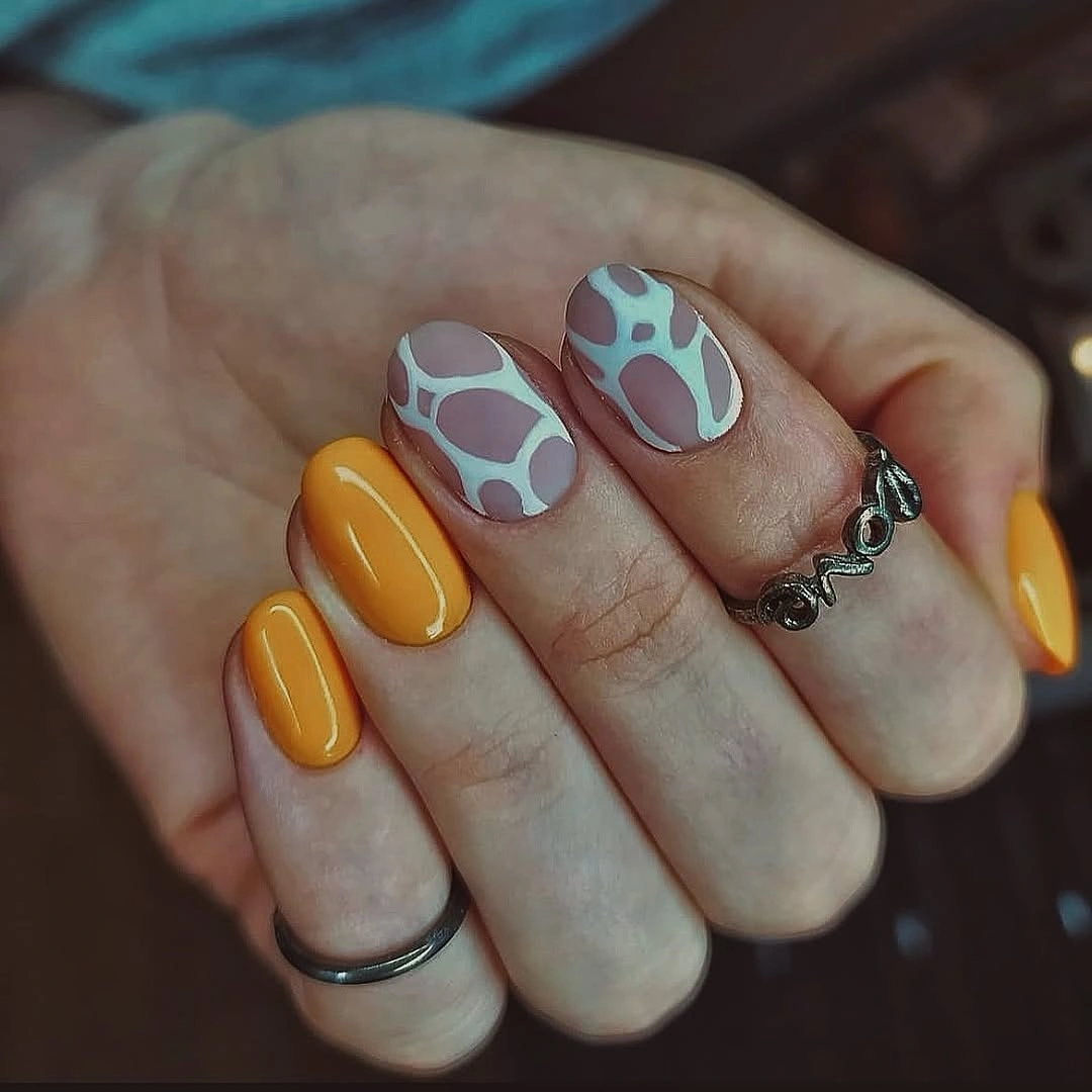 Short rounded nails with mustard polish and abstract blue patches