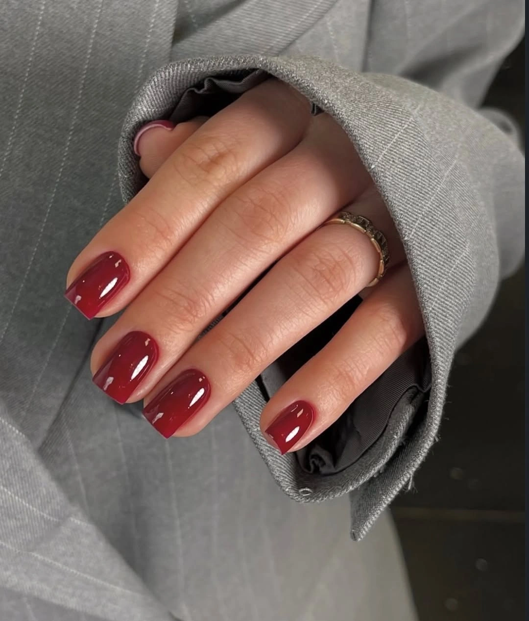 Glossy burgundy short square nails with a gray sleeve