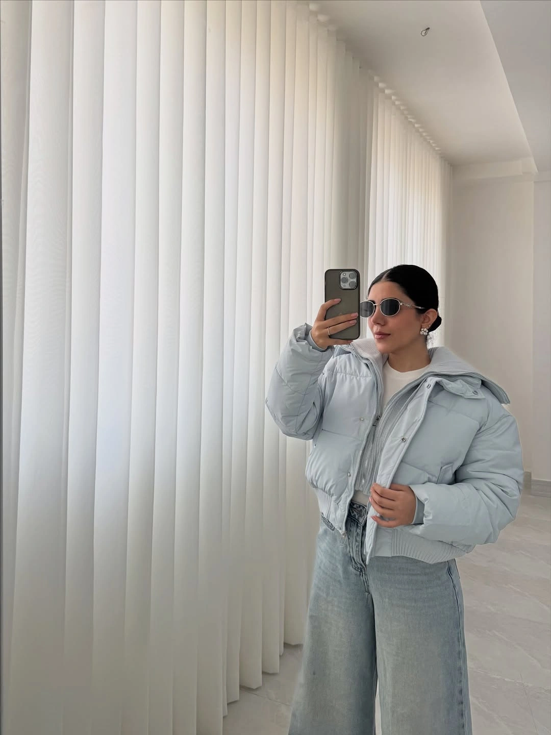 pale gray cropped puffer with washed wide jeans layered waistband and sunglasses