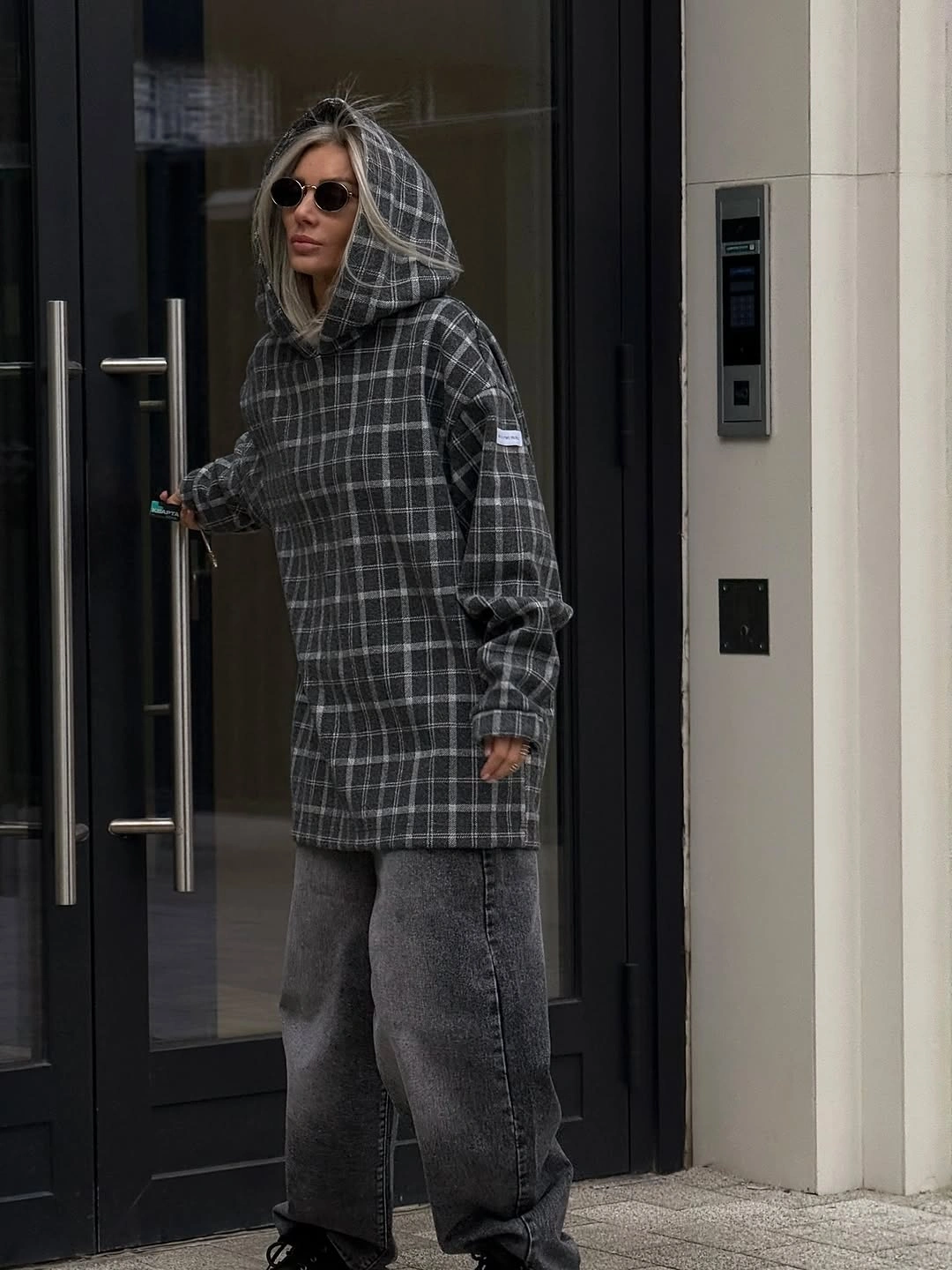 gray plaid hooded jacket with faded wide gray denim and dark sunglasses