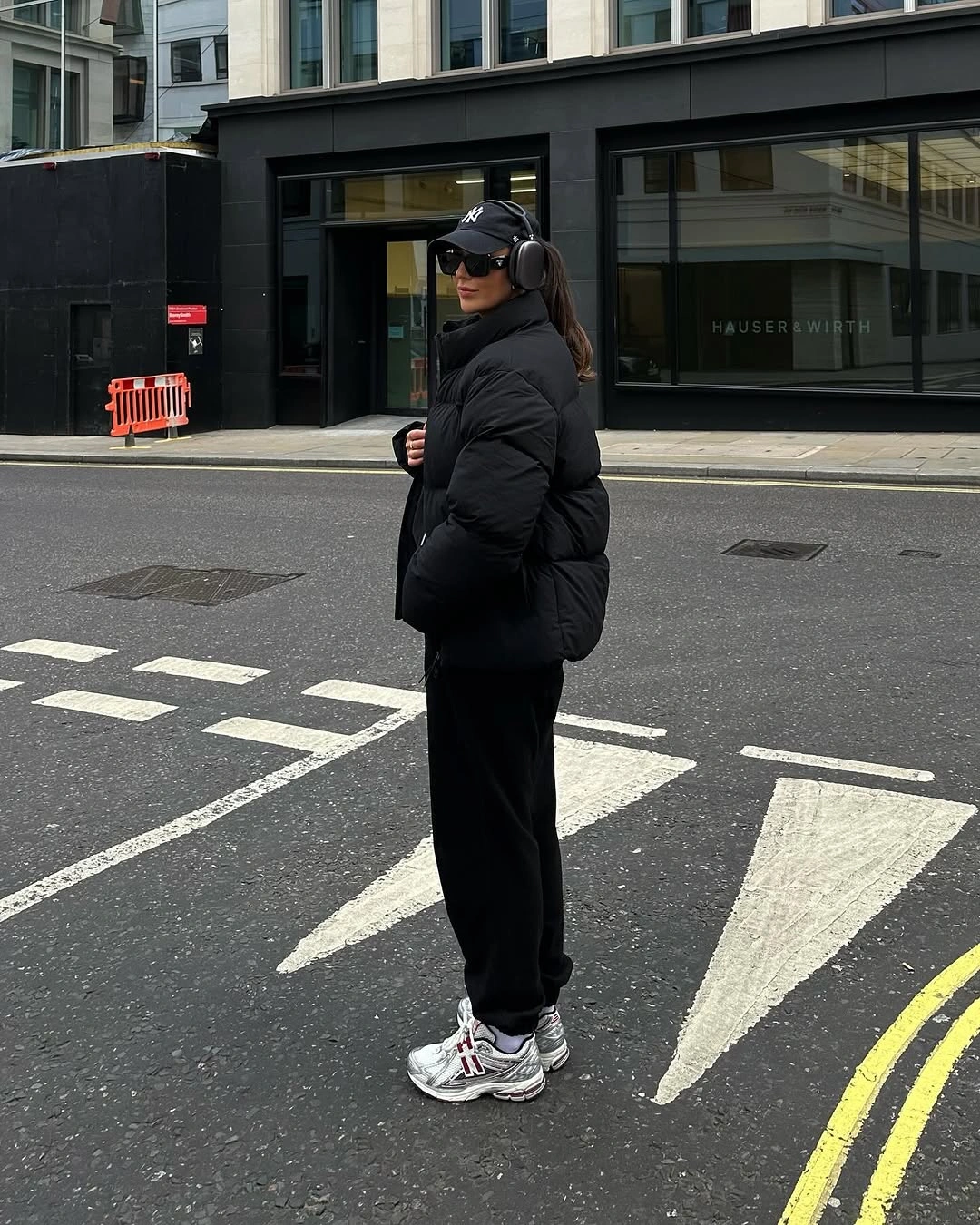 black puffer cap headphones black joggers and silver white running shoes