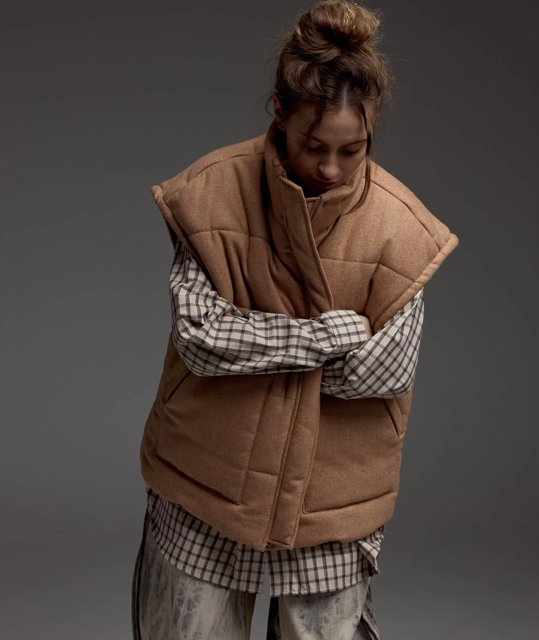 oversized brown puffer vest over long brown plaid shirt layers