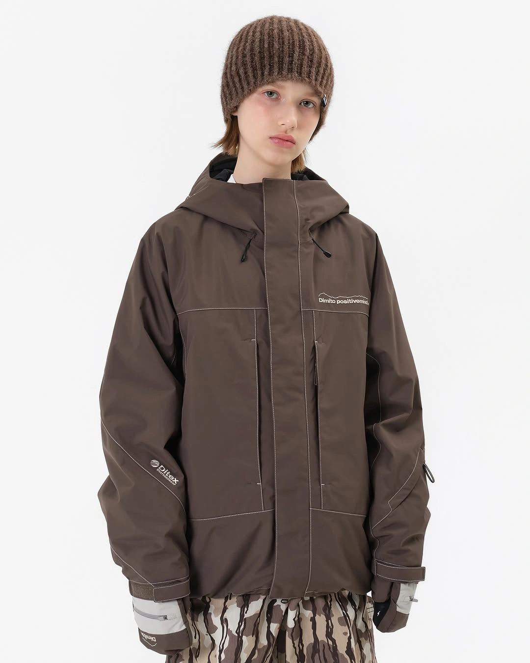 chocolate hooded technical jacket with loose patterned brown trousers and knit beanie