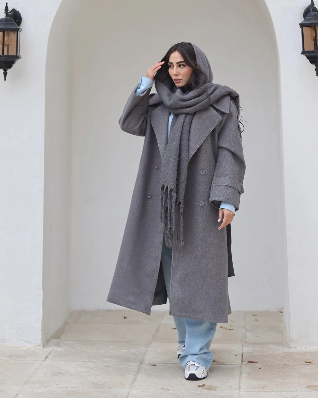 long gray coat and scarf with pale blue wide jeans and white sneakers
