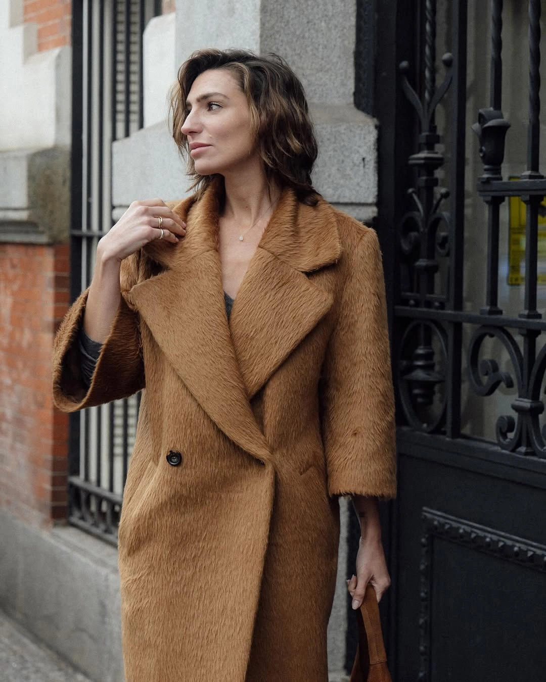 Textured camel long coat with wide lapels and brown bag