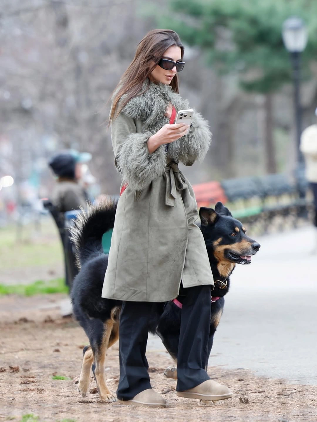 Sage-grey belted coat with plush-looking trim and dark trousers