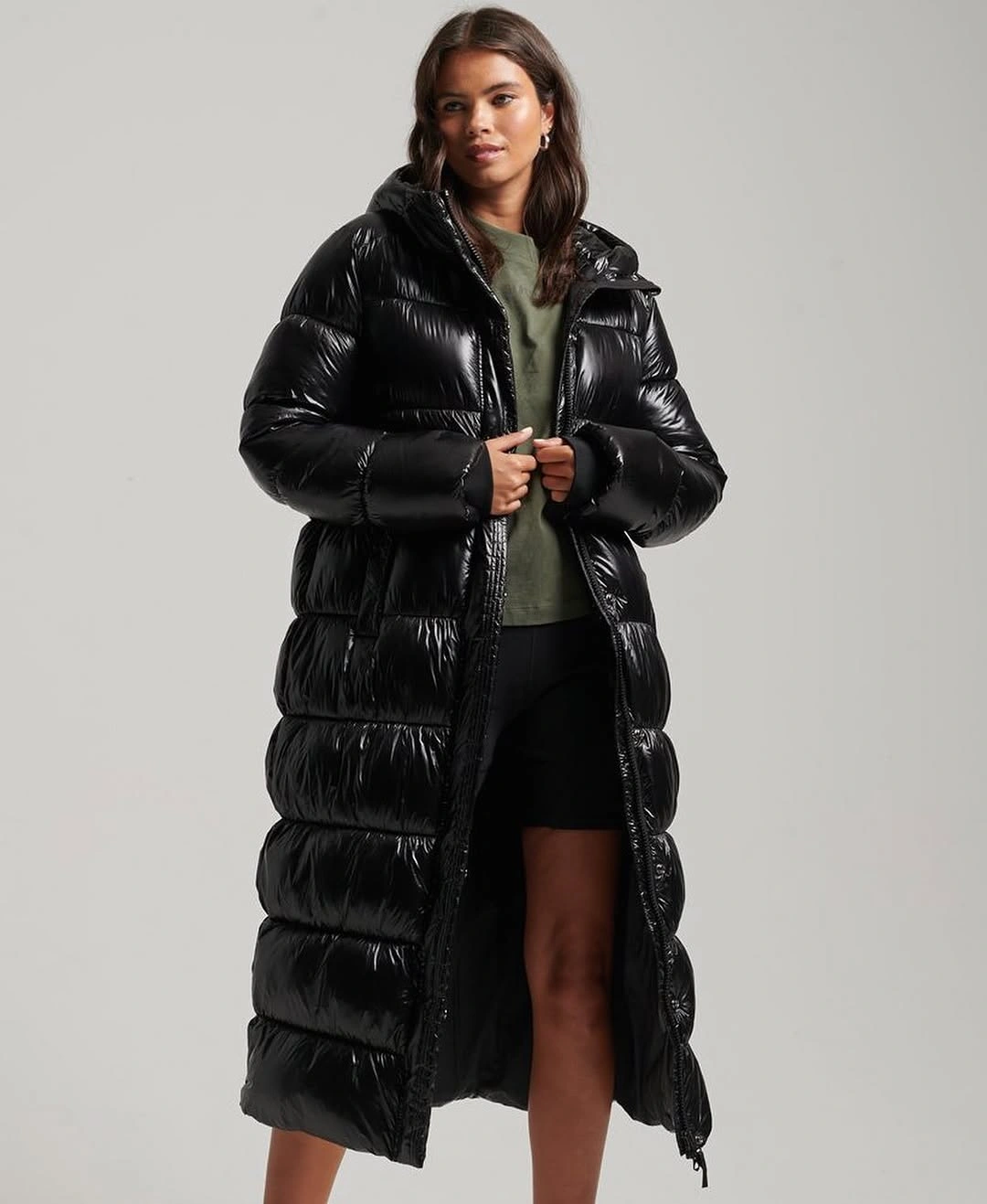 Long black glossy hooded puffer coat over short black layer