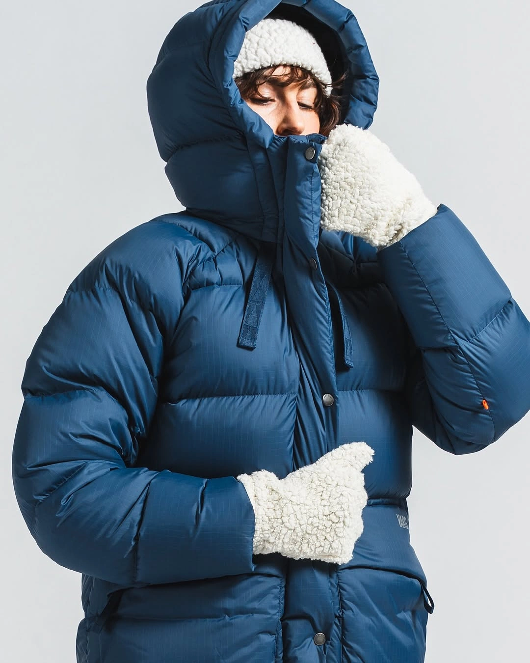 Deep blue hooded puffer with white hat and fuzzy gloves