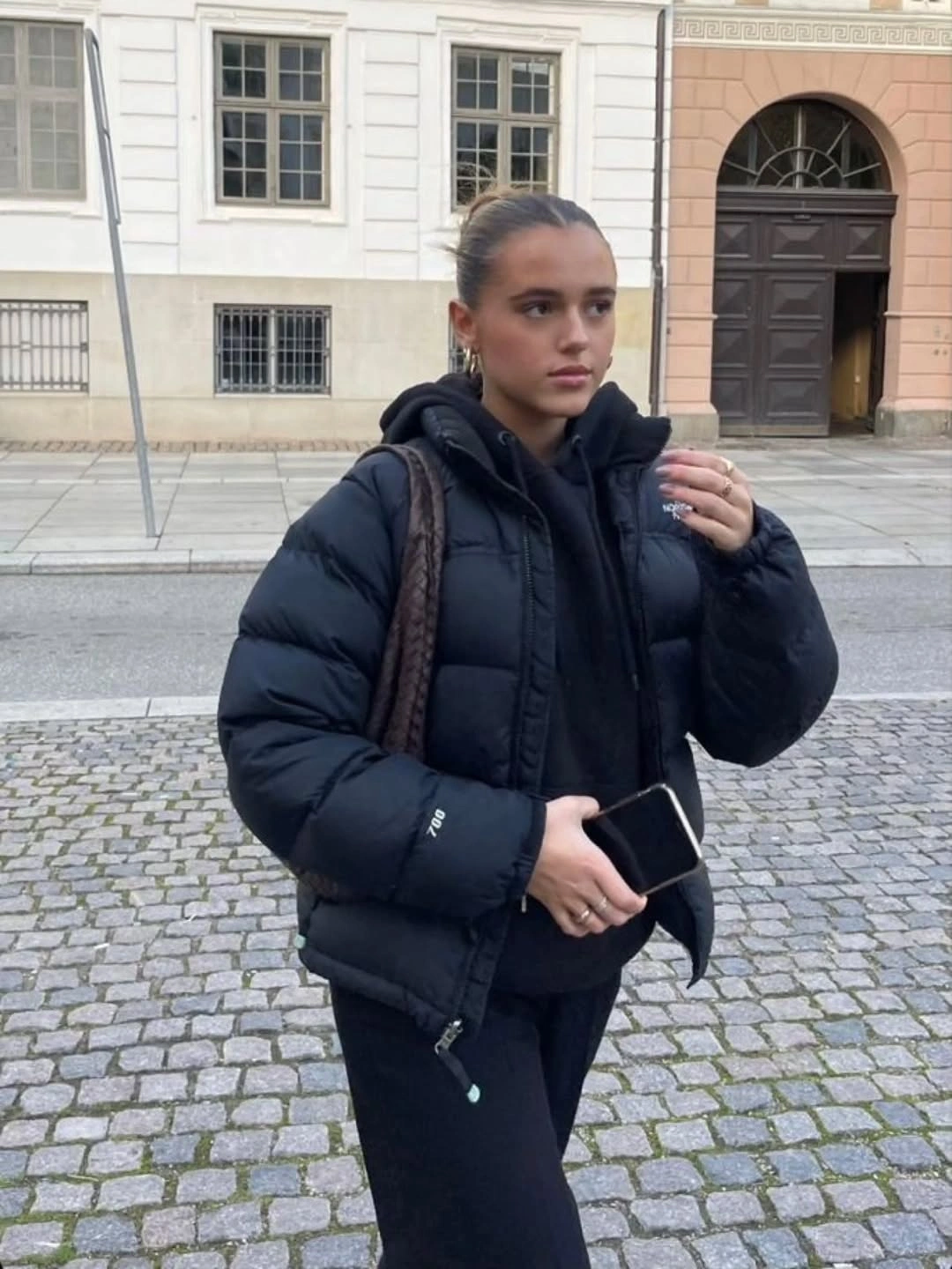 Black cropped puffer over black hoodie and slim pants
