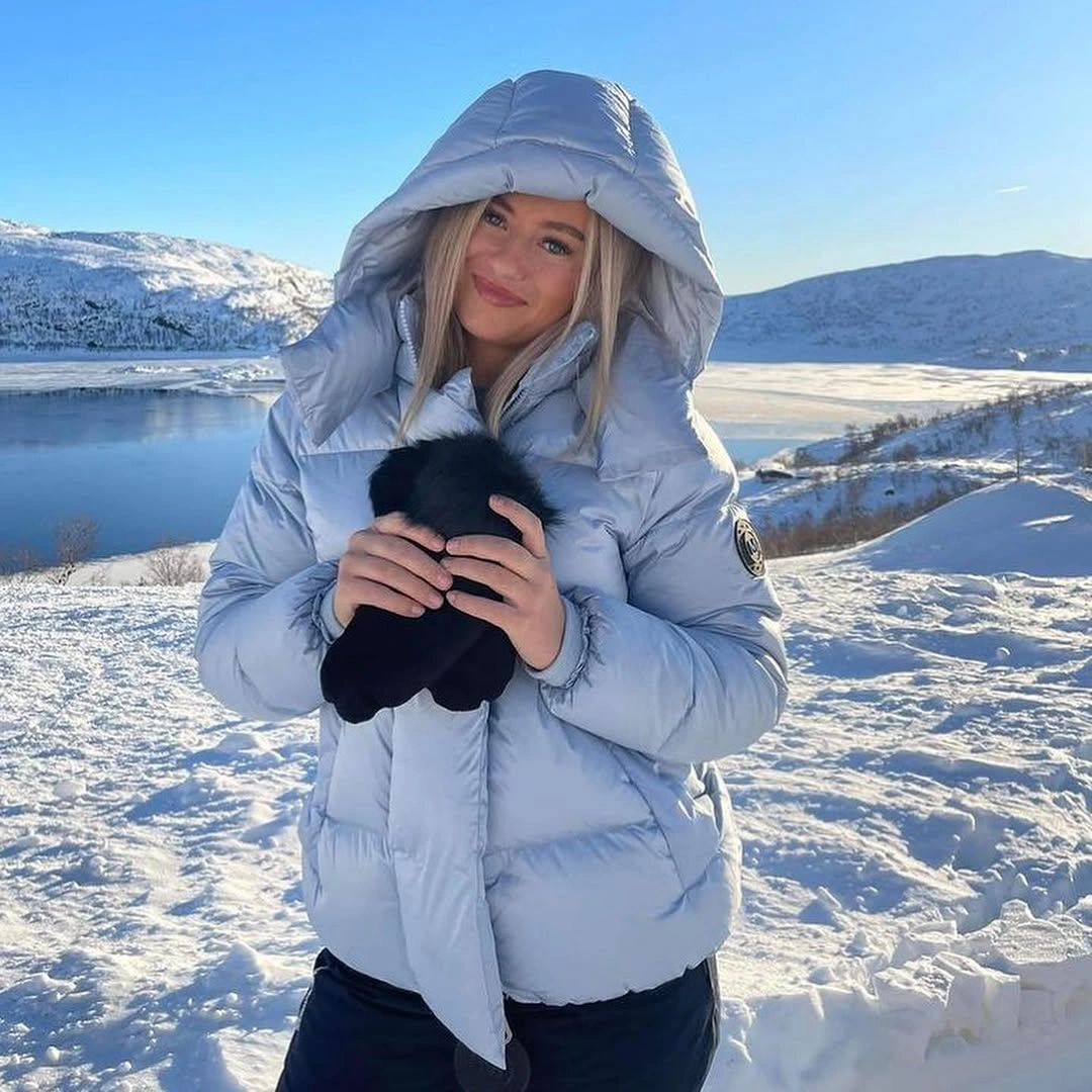 Icy blue hooded puffer with black gloves in snow