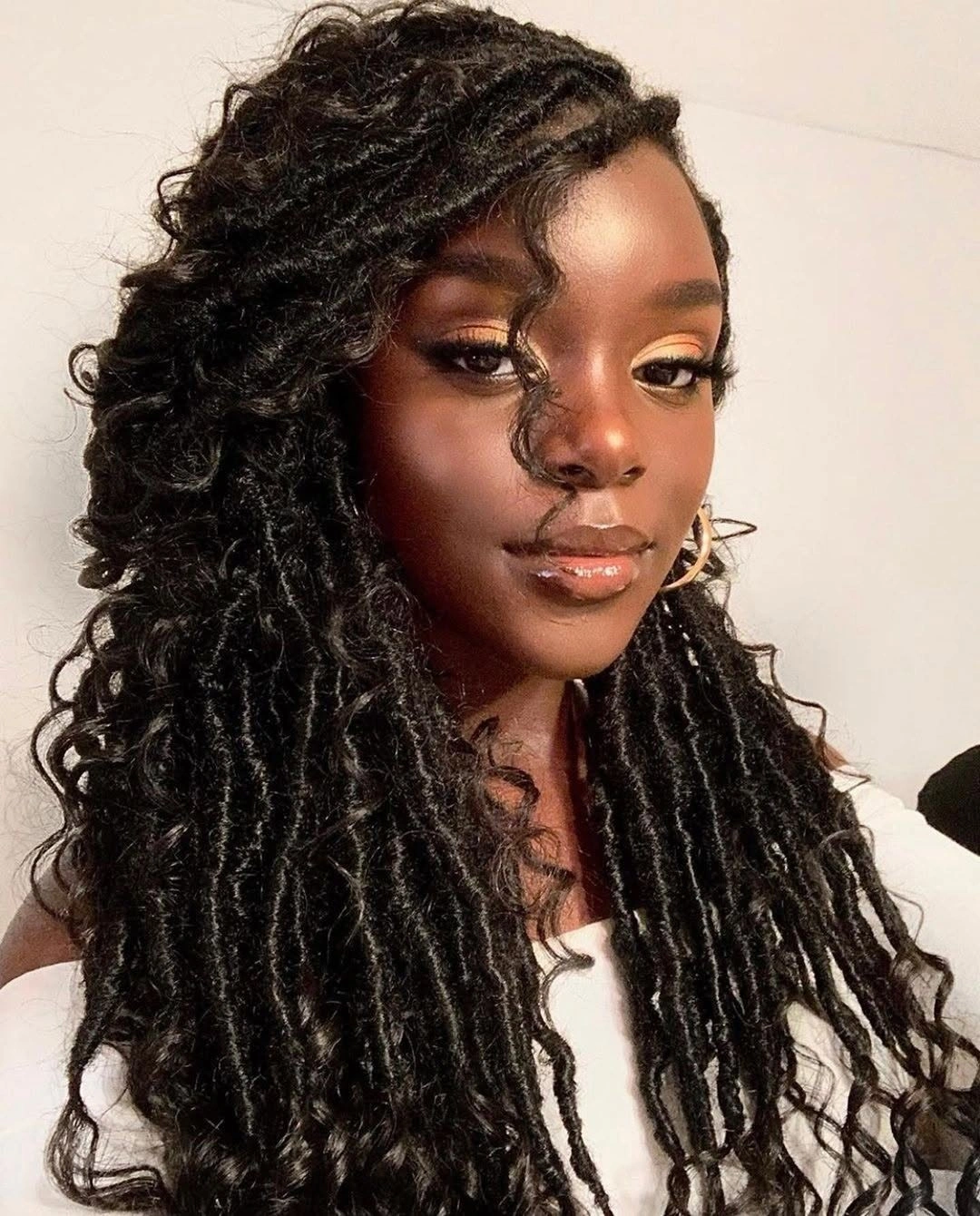 Long dark locs with side part and curled face tendril