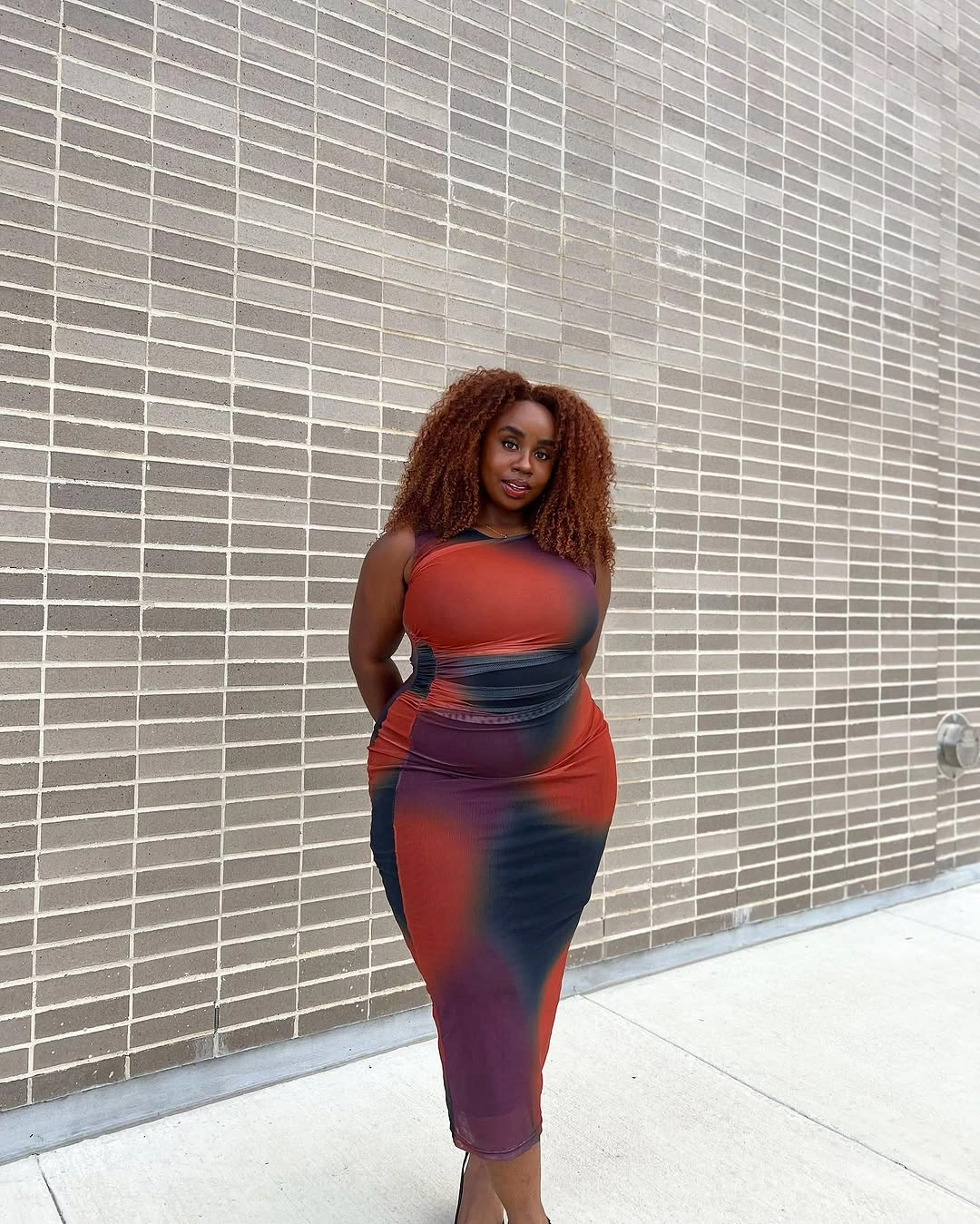 Copper-orange curls around shoulders with fitted patterned dress