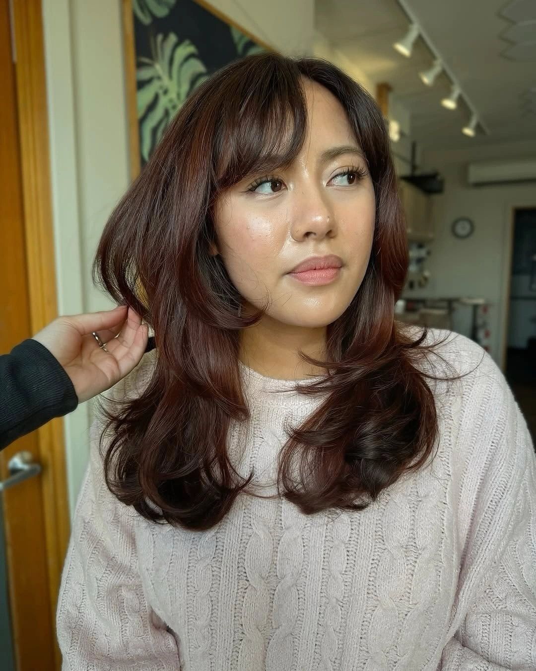 Long auburn layered hair with parted bangs and curled ends