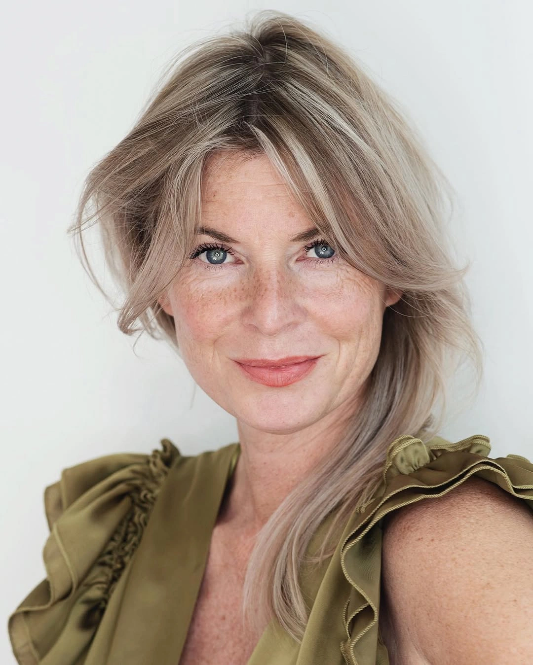 Long pale blonde layered hair with side-swept feathered front