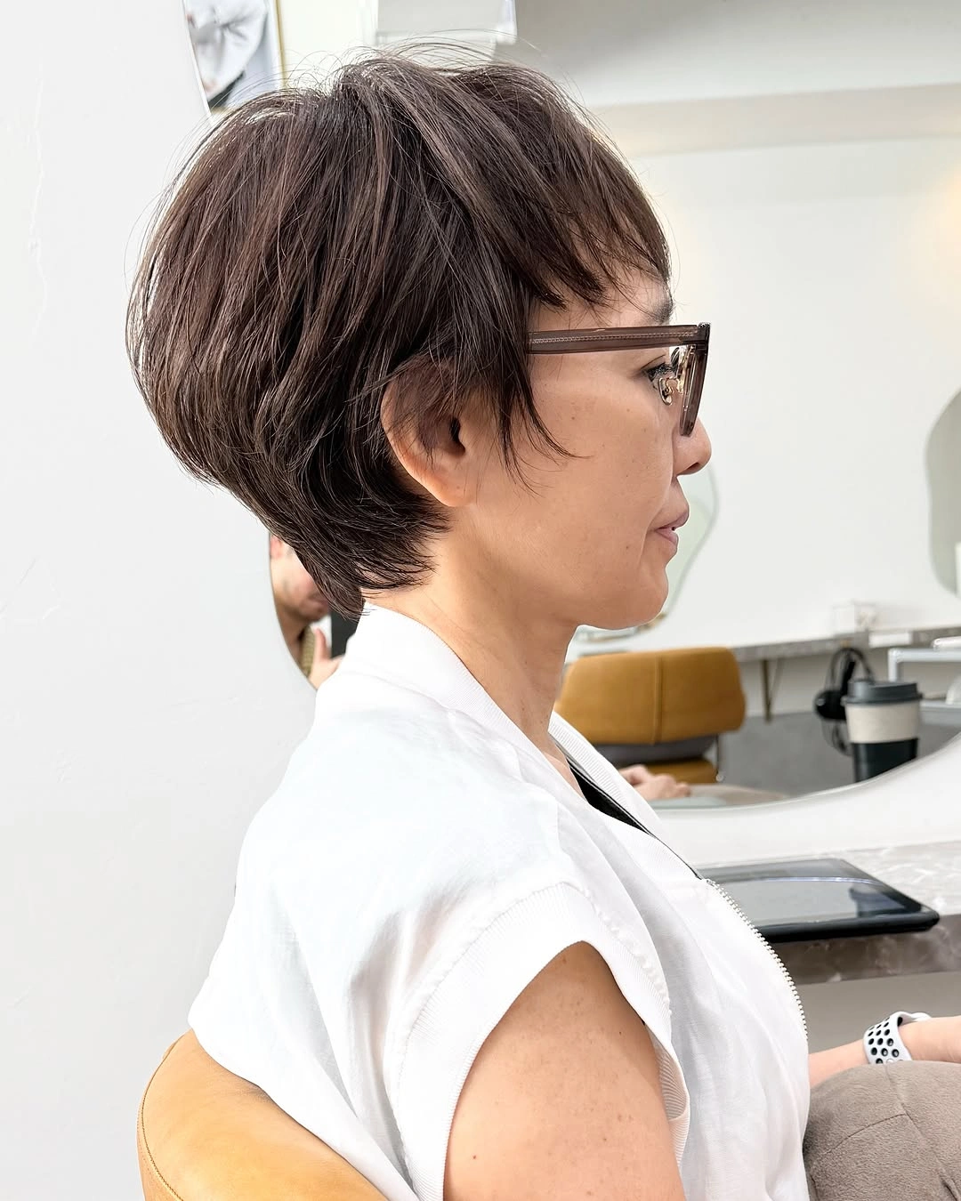 Short dark layered haircut with glasses and tapered nape