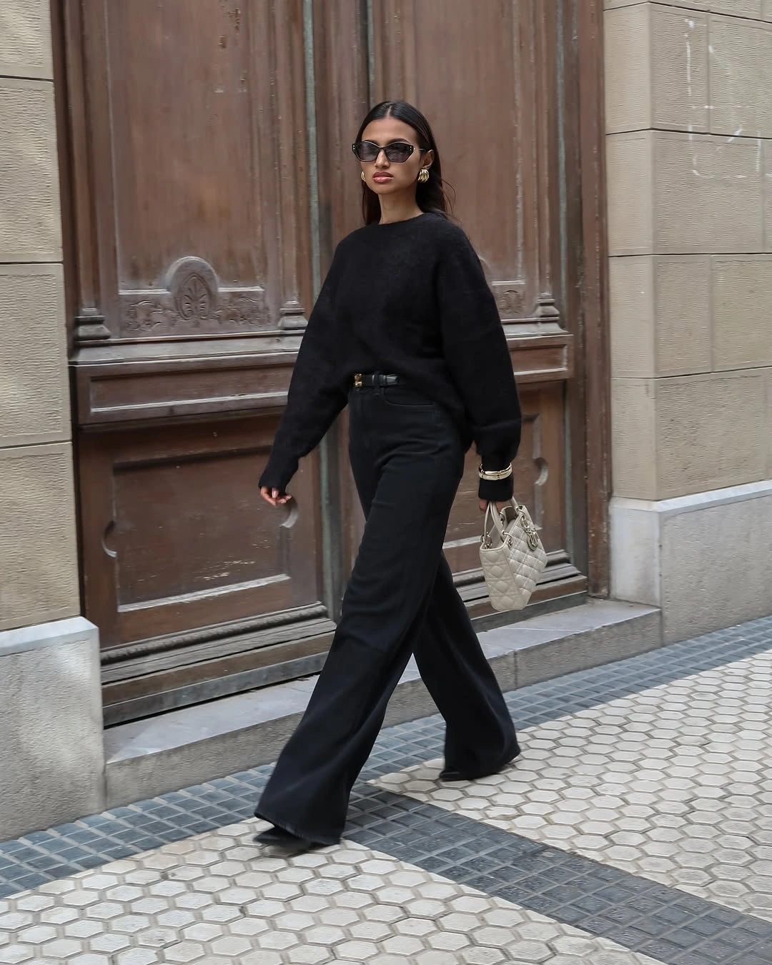 Black sweater and trousers with pale woven handbag
