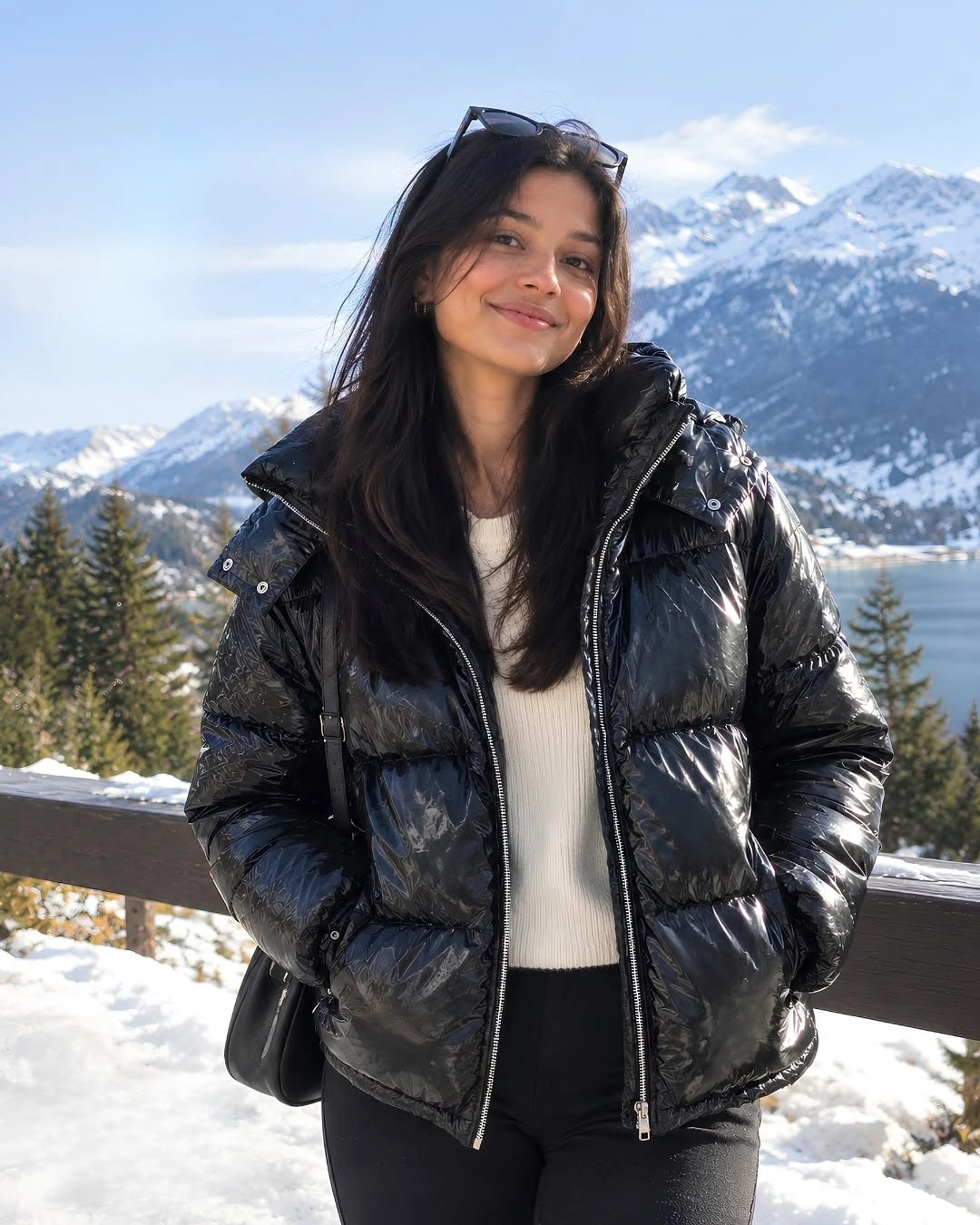 Glossy black puffer over white knit in snowy mountains