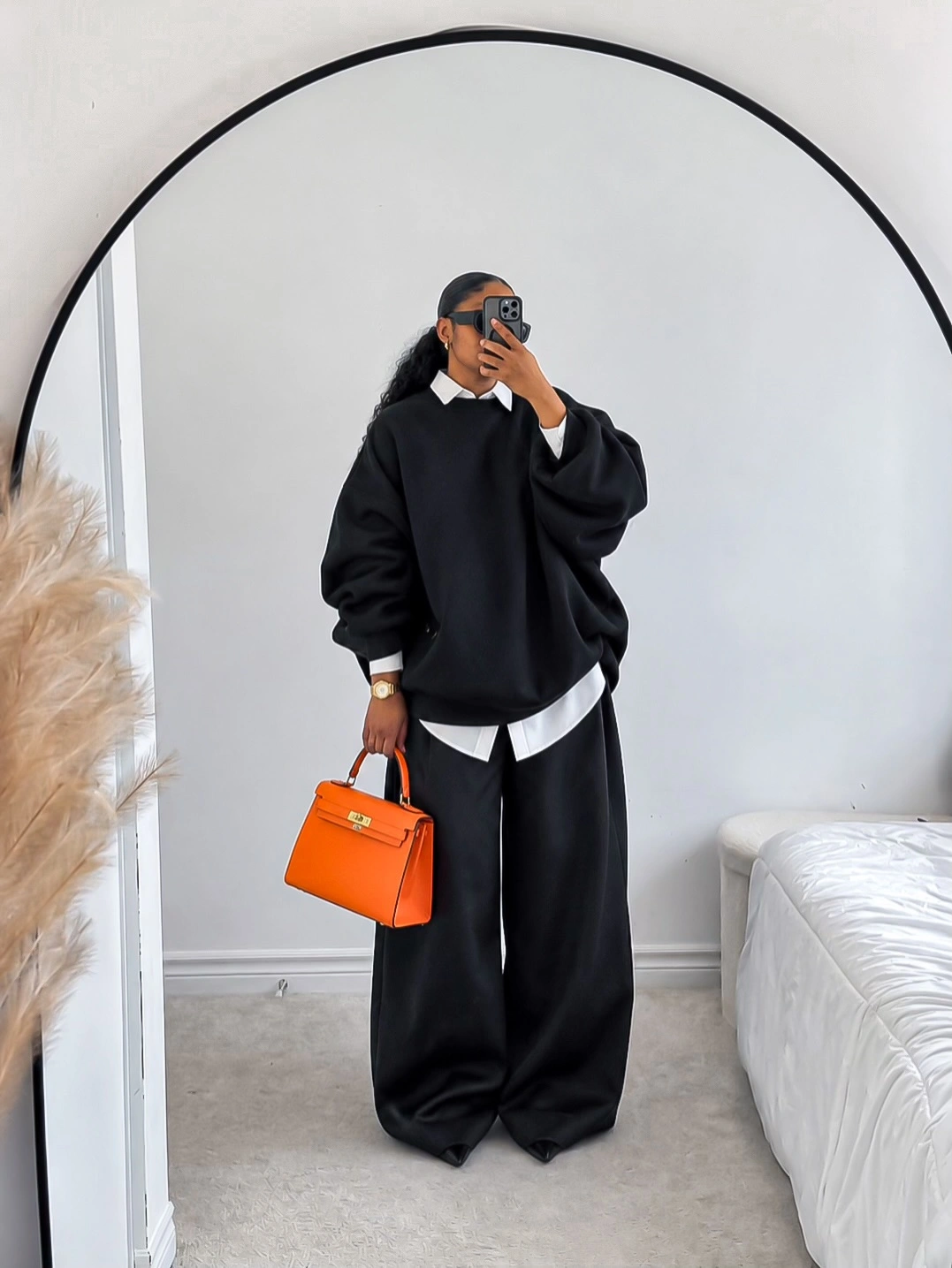 Oversized black sweatshirt with white shirt and orange handbag
