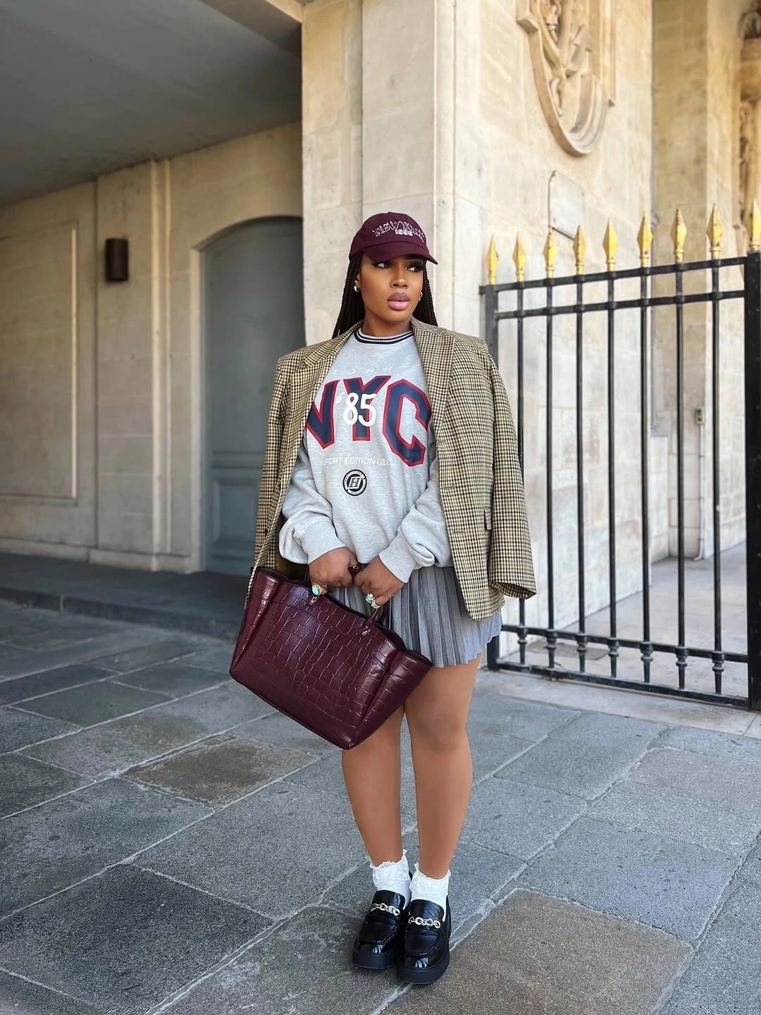Burgundy cap, varsity sweatshirt, checked blazer and pleated skirt
