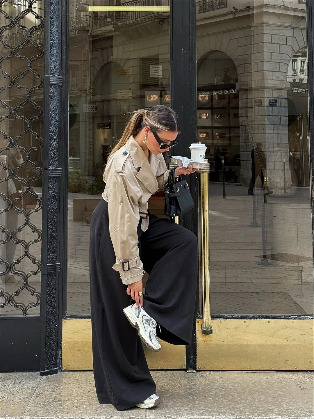 Cropped beige trench jacket, black wide trousers and white sneakers