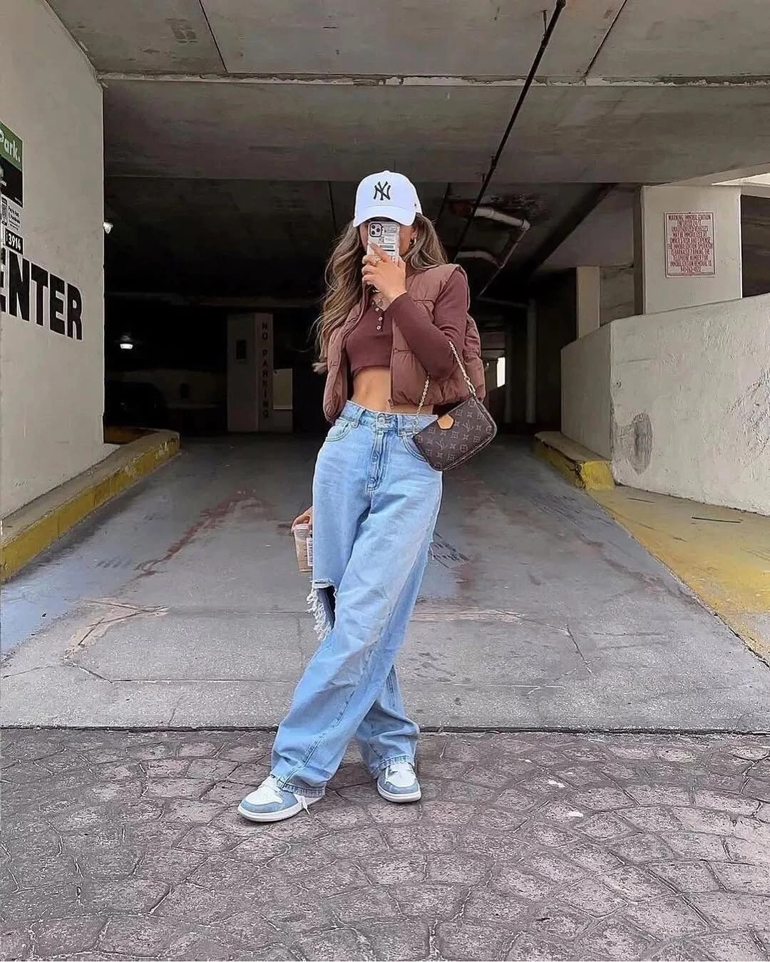 White cap, cropped brown top, loose jeans and sneakers