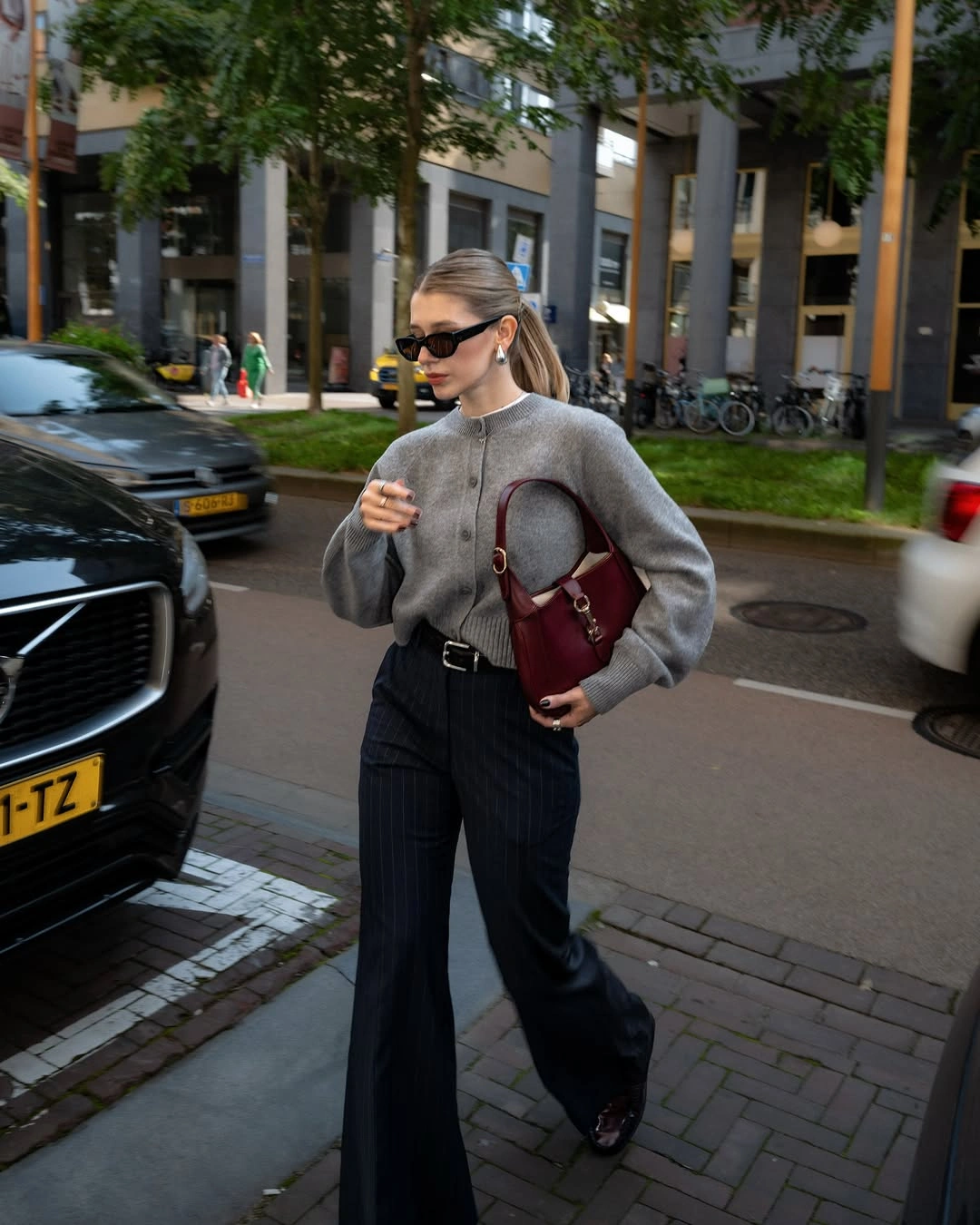 Gray sweater with pinstriped wide trousers and burgundy shoulder bag