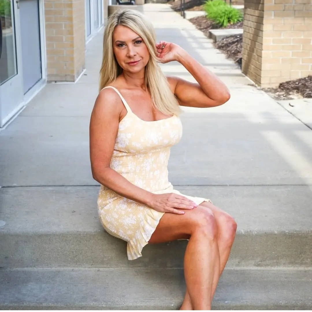 Woman in pale yellow floral thin-strap dress on concrete steps
