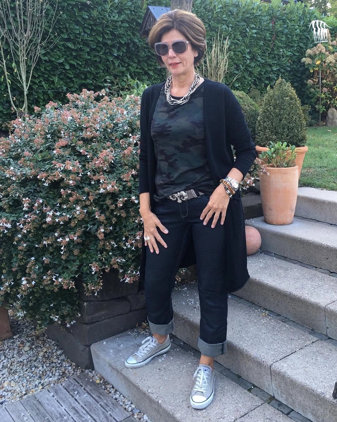 Dark cardigan, printed tee, cuffed black jeans and gray sneakers