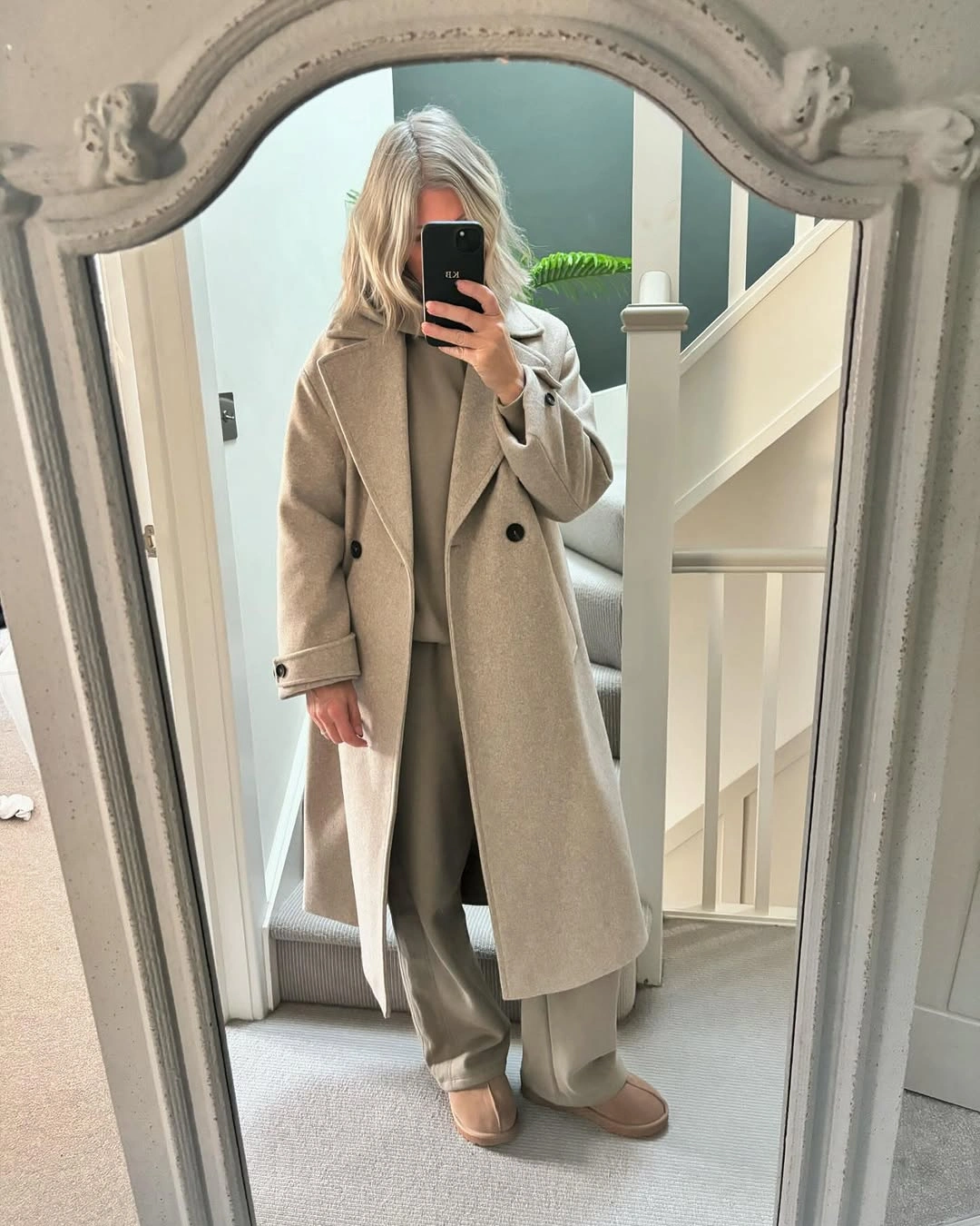 Long beige coat with tonal layers, wide trousers and pale shoes