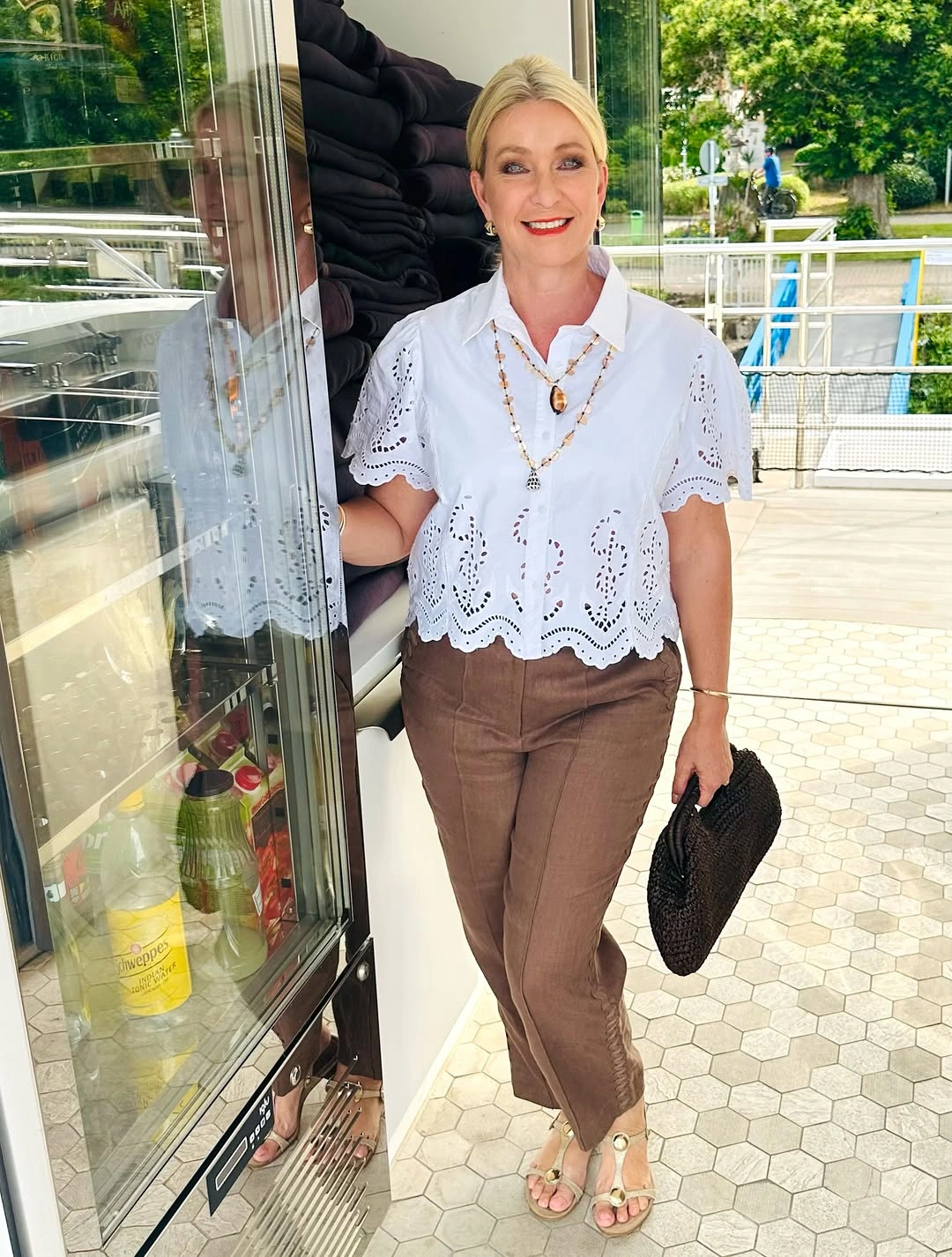 White eyelet blouse with brown trousers, sandals and black woven bag