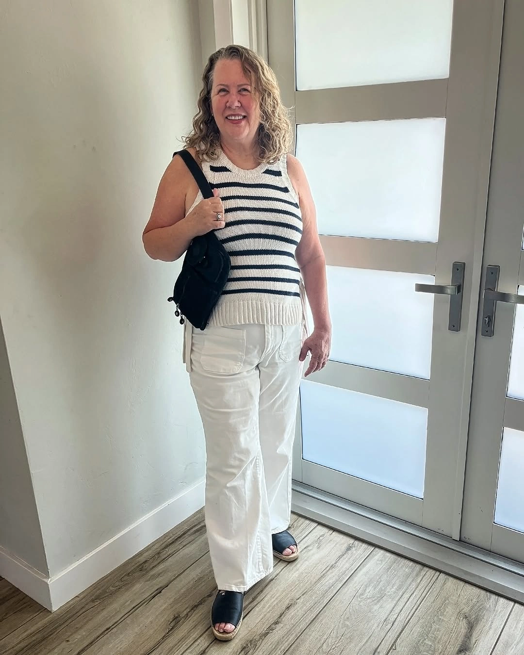 Cream sleeveless striped top with white trousers and black accessories