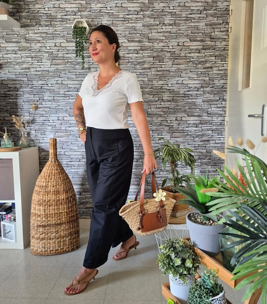 White lace-trim top with black trousers and woven handbag