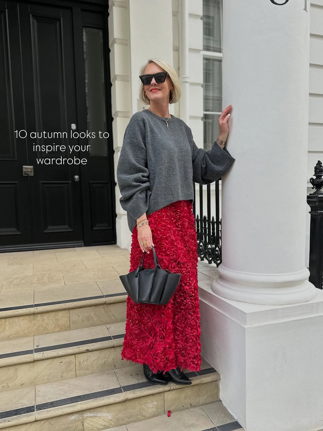 Gray sweater with red textured skirt, black boots and handbag
