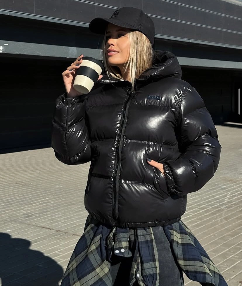 Glossy black hooded puffer with cap and plaid shirt tied at hips