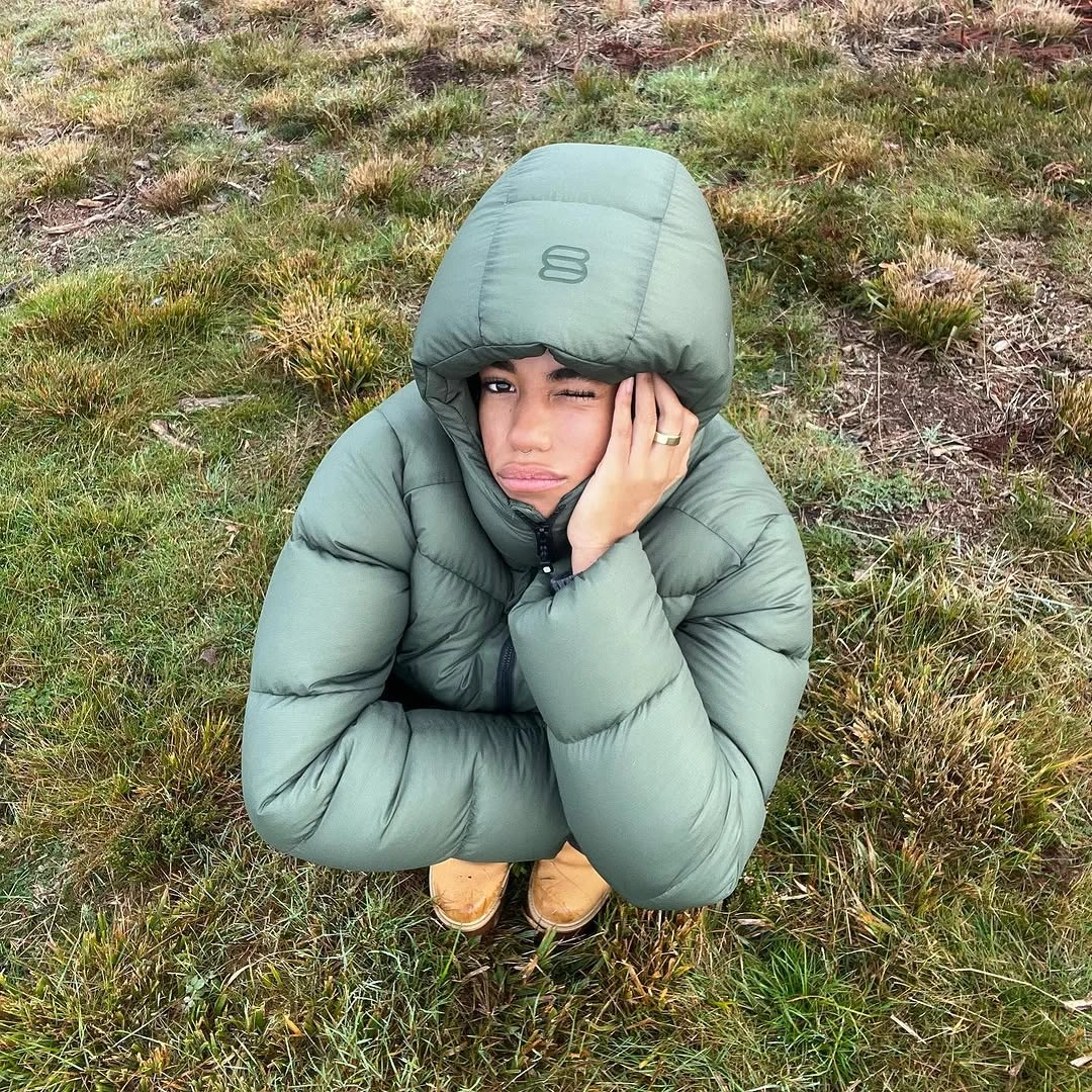 Sage green hooded puffer with oversized hood and tan boots