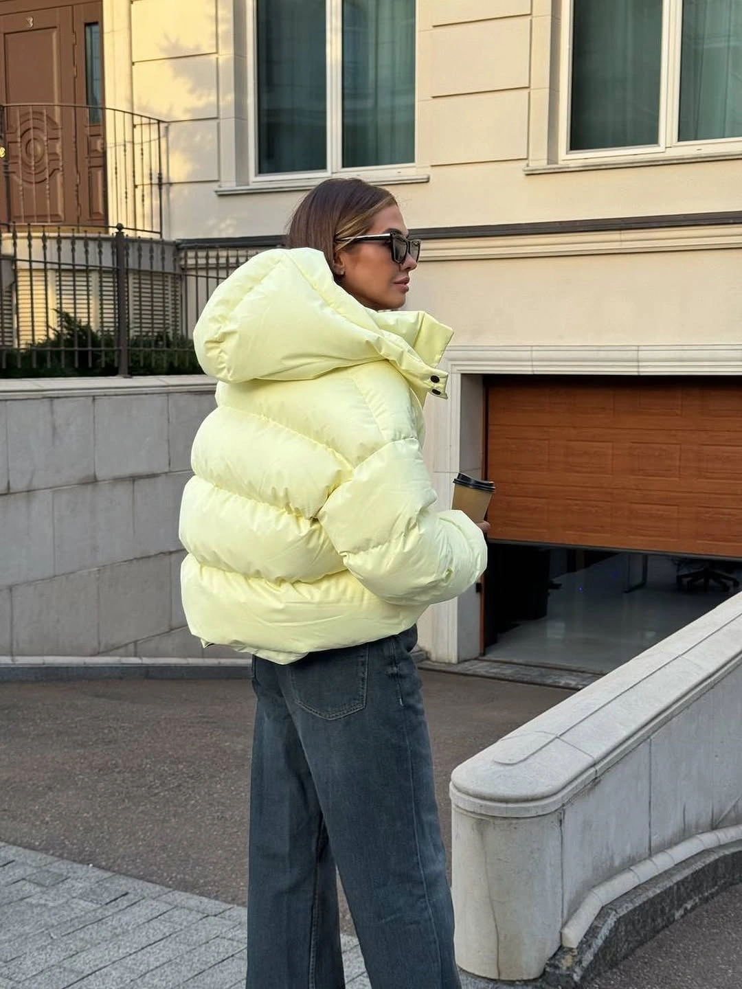 Pale yellow-green cropped puffer with hood and wide dark jeans